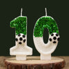 Two white candles shaped like the numbers 1 and 0 decorated with green glitter resembling soccer balls