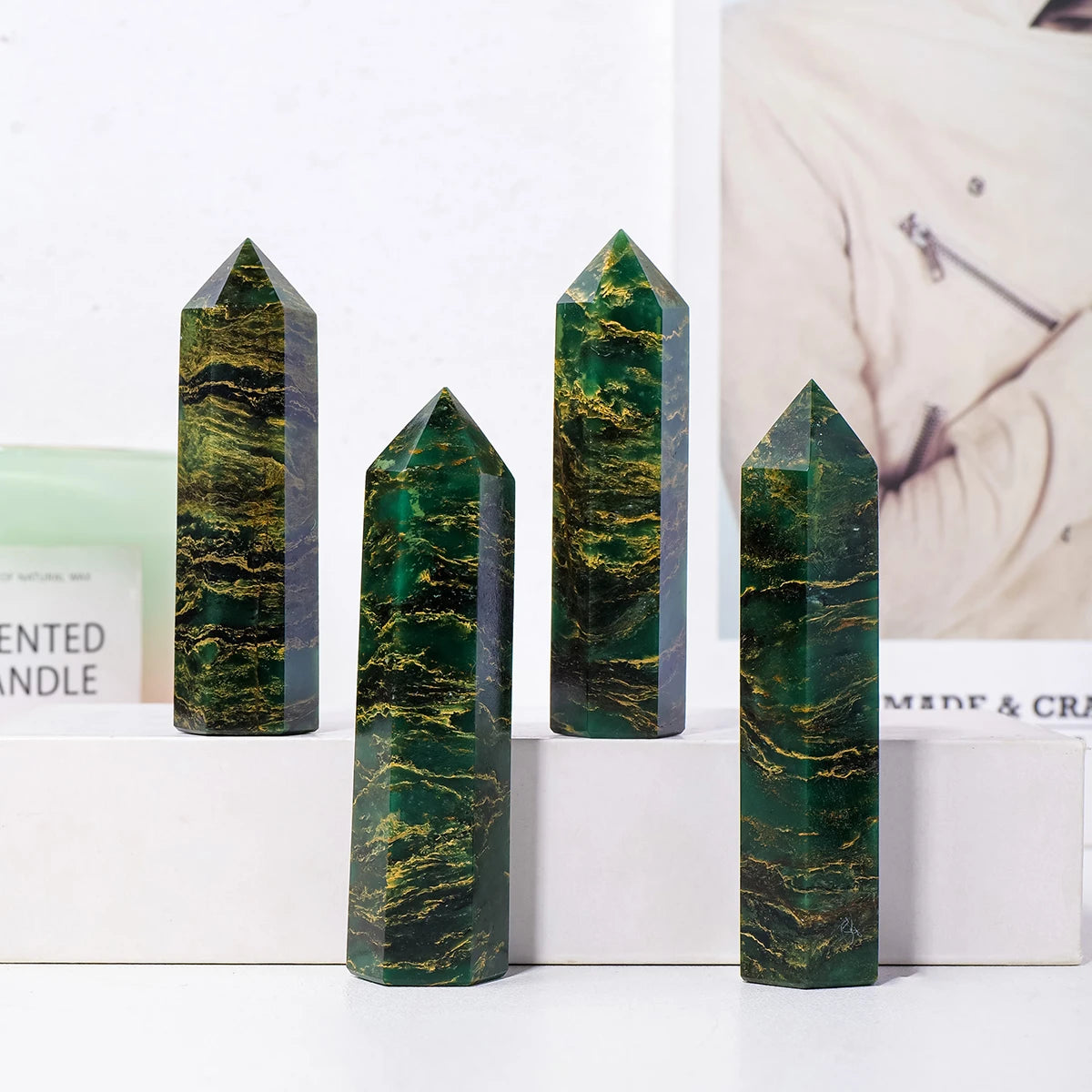 Four dark green emerald crystal point healing wands displayed vertically on a white surface.