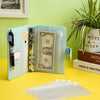 A light blue A6 PU leather budget planner binder with cash envelopes and expense sheets displayed on a green surface.