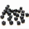 A pile of small, square cut black glass crystal beads for jewelry making.