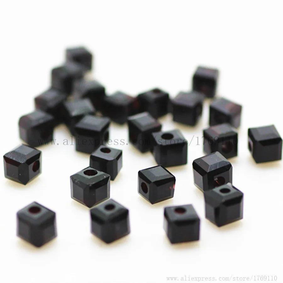 A pile of small, square cut black glass crystal beads for jewelry making.