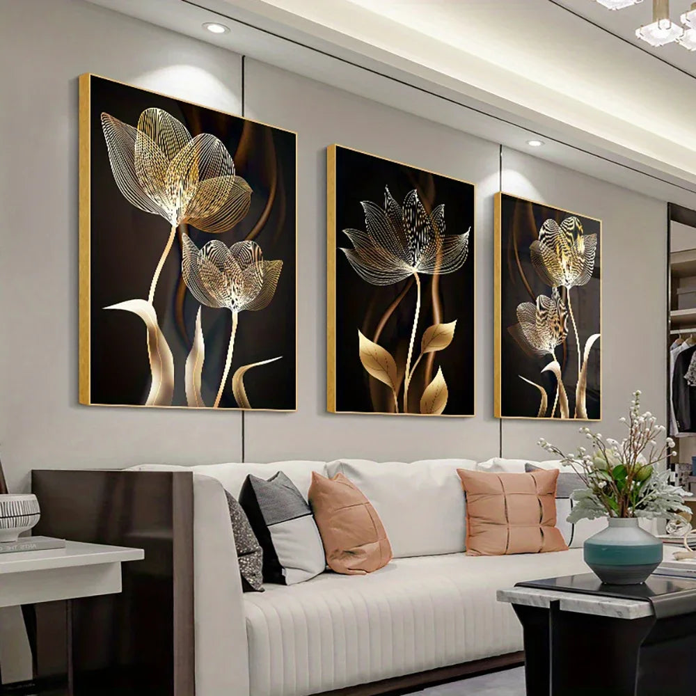 A set of three abstract flower canvas wall art pieces featuring golden and black tones displayed in a modern living room.