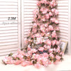 A long garland of pink artificial sakura flowers draped against a white slatted background.