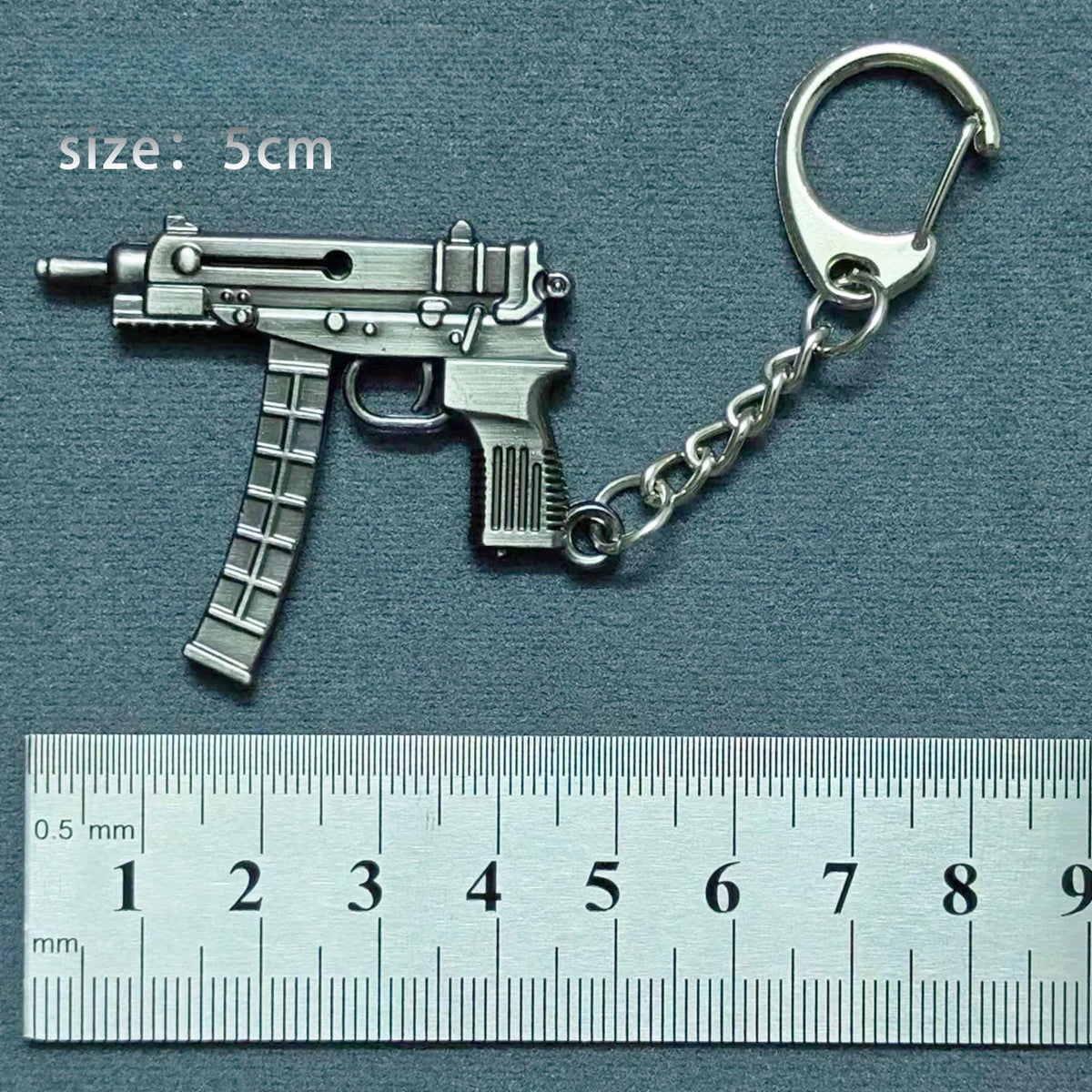 A silver alloy gun model miniature keychain featuring a realistic replica of a firearm attached to a chain.