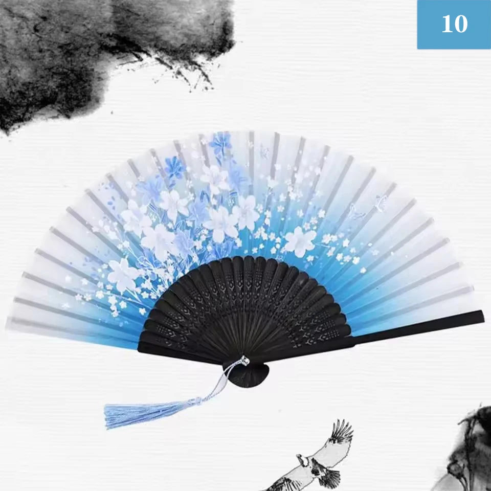 A vintage silk bamboo folding hand fan with blue and white floral designs shown open.