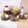 A set of five decorative wooden riser stands displaying various desserts and a bottle of Malibu liquor.