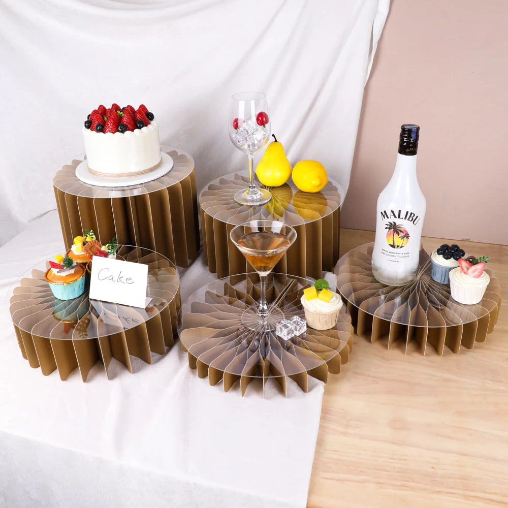A set of five decorative wooden riser stands displaying various desserts and a bottle of Malibu liquor.