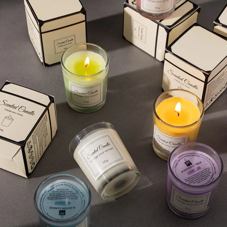 A collection of scented candles in glass jars and boxes, showing various colors like yellow, green, and purple.