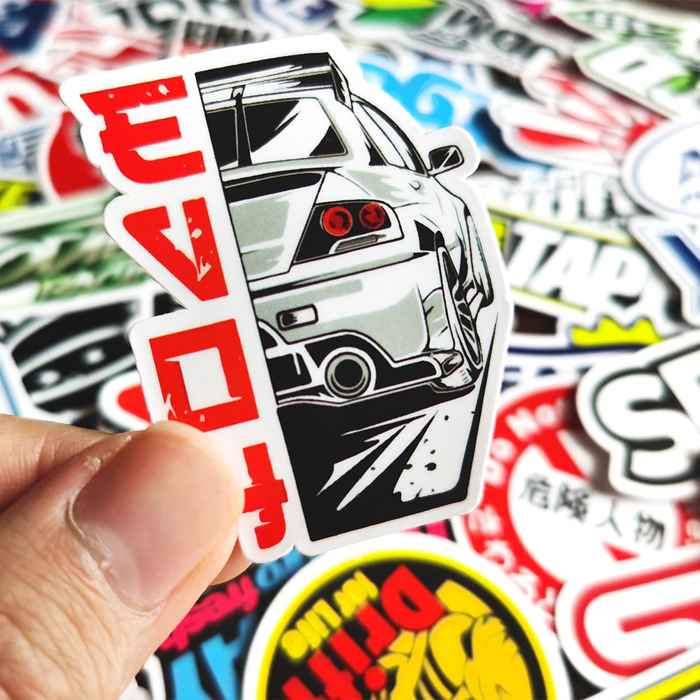 A hand holds a die-cut vinyl decal sticker featuring a stylized white car headlight design with red accents.