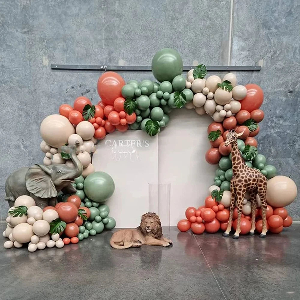 An archway decorated with a lush garland of sand white, green, and coral latex balloons surrounding a white sign.
