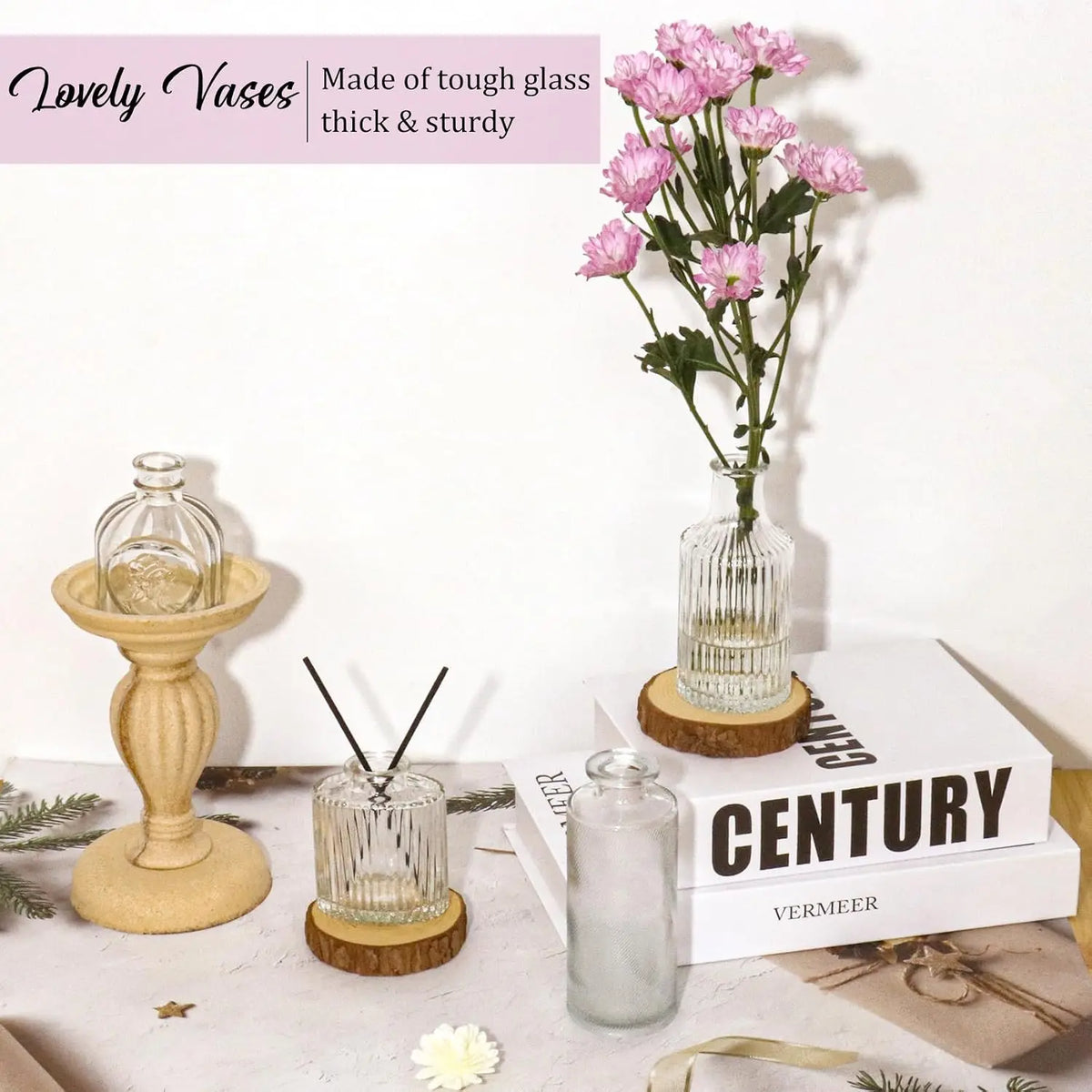 A set of vintage bud glass vases displayed on a white surface with pink flowers and natural wood accents.