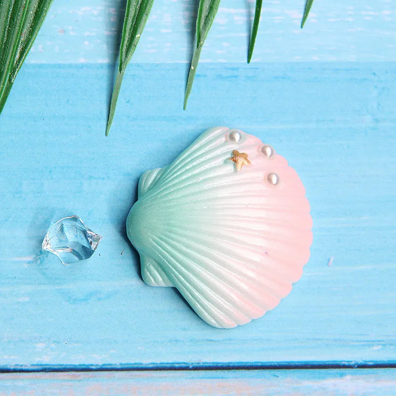 A pale pink seashell with vertical ridges and small pearl accents rests on a light blue wooden surface.