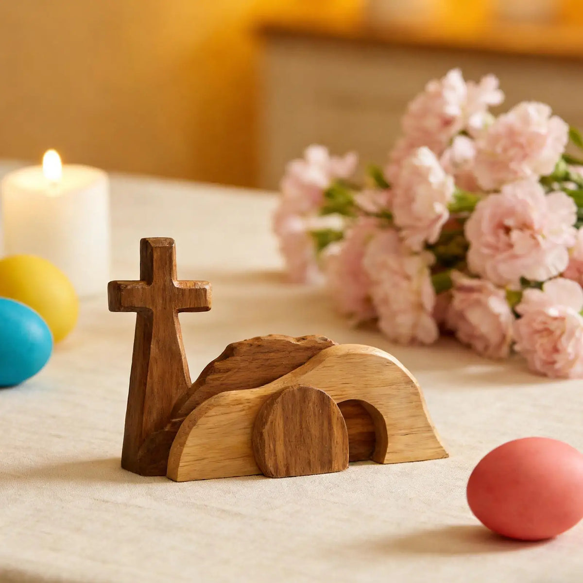 A wooden Easter empty tomb scene decoration featuring a cross and a tomb structure on a white surface.