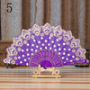 Elegant lace folding hand fan in purple and white with gold detailing displayed on a wooden stand.