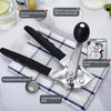 A silver manual can opener with a black handle and oversized knob, shown next to a cloth napkin.