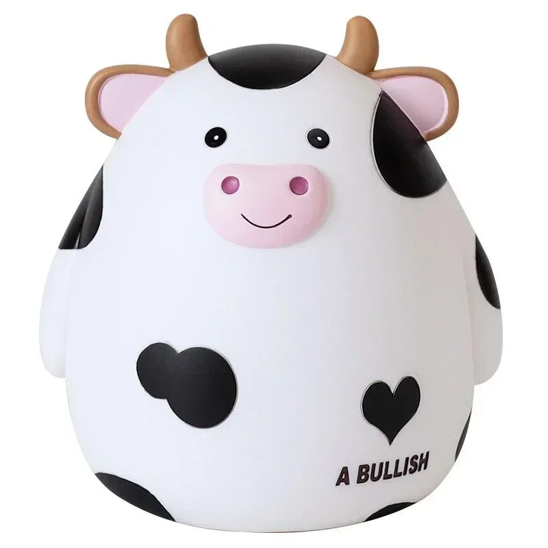 A cartoon cow piggy bank coin holder with white and black markings and pink accents.