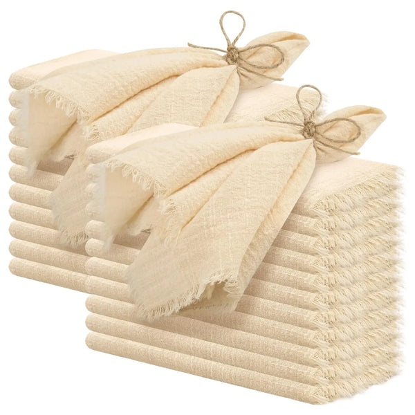 A stack of ten handcrafted fringed cotton napkins in a natural beige color.