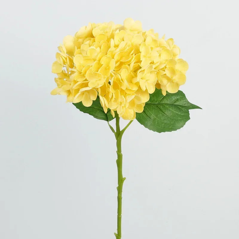 A cluster of bright yellow artificial hydrangea flowers on a green stem and leaf.