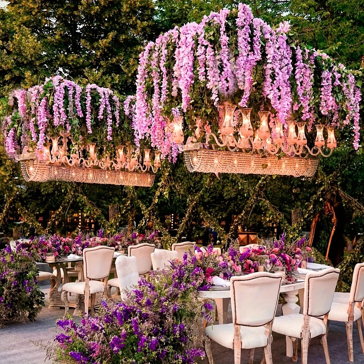 An outdoor event decorated with hanging floral chandeliers made of artificial wisteria vine garlands and purple flowers.