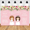 A pink and green floral backdrop for a First Communion celebration featuring two girls in white dresses