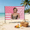 A decorative flag banner featuring pink and white stripes with stars, set up on a beach with a woman in front.