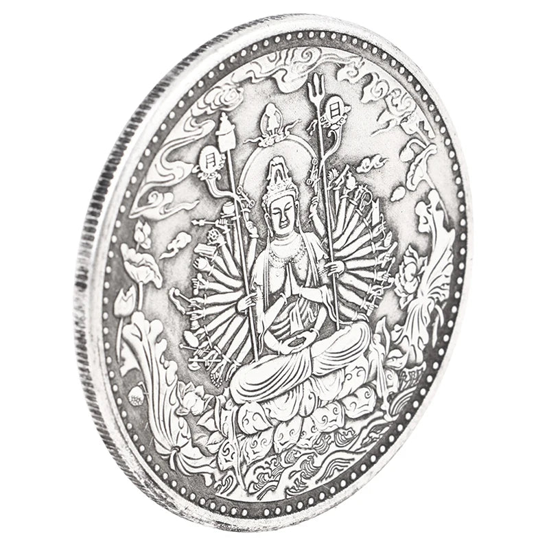 A silver-toned medallion depicting a seated Buddha figure with multiple arms and various ancient symbols.