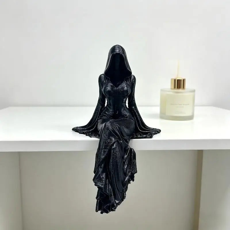 Schwarze Harzfigur einer weiblichen Gestalt in einem fließenden Kleid, neben einer Glasflasche ausgestellt.