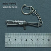 A silver alloy gun model miniature keychain with a chain and jump ring, shown next to a ruler.