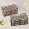 Clear acrylic jewelry organizer with three drawers displaying various rings and earrings.