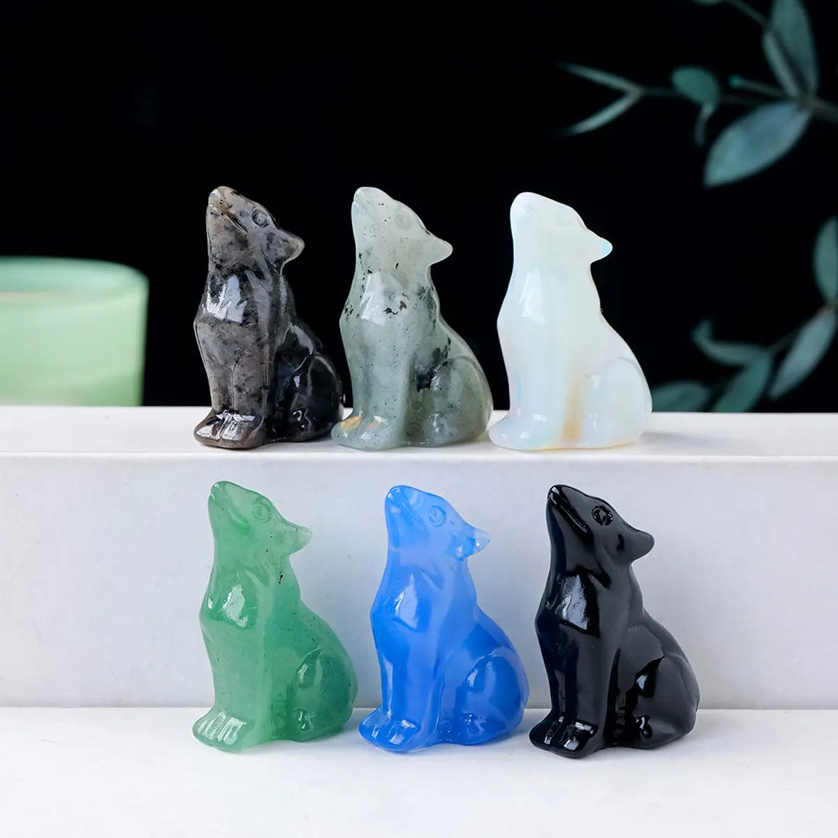 Eine Sammlung natürlicher Wolfskristallfiguren in verschiedenen Grautönen, Weiß und Blau, präsentiert auf einer weißen Oberfl