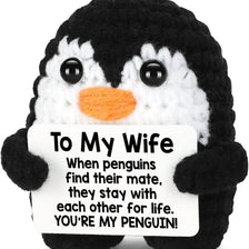 Black and white penguin crochet doll with an orange beak and a card that reads To My Wife You're my penguin