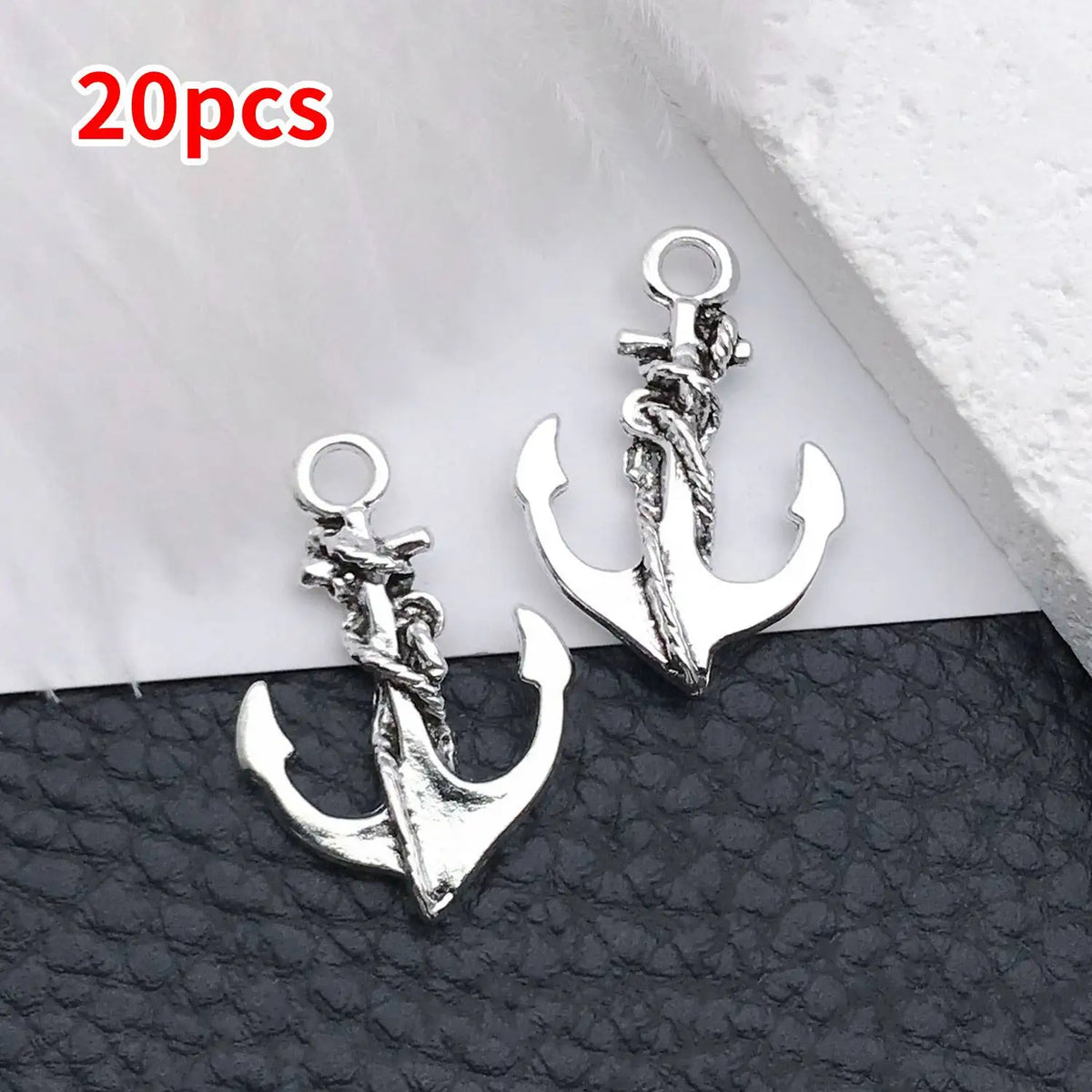 20 pieces of silver vintage ship anchor charms for jewelry making displayed on black leather.