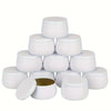 A set of white metal candle tins with lids arranged in a pyramid formation.
