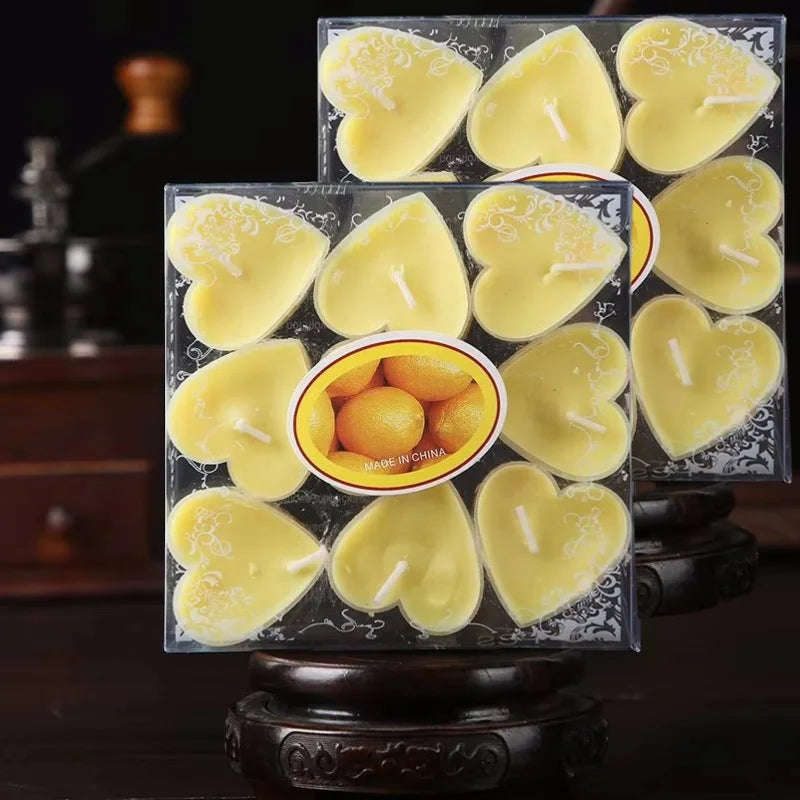 Un set de bougies parfumées en forme de cœur jaune emballées dans des contenants carrés transparents.