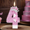 A glittery pink number four candle with butterfly accents on a wooden surface.