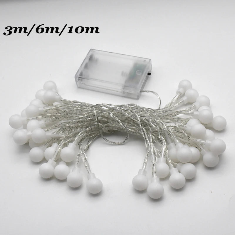A bundle of white globe string lights with thin wires and a clear battery pack.