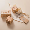 A set of wooden baby milestone cards featuring numbers and text, tied with twine on a neutral background.