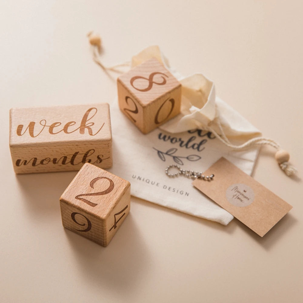 A set of wooden baby milestone cards featuring numbers and text, tied with twine on a neutral background.