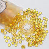 A pile of small, translucent yellow wax sealing beads scattered on a white surface.