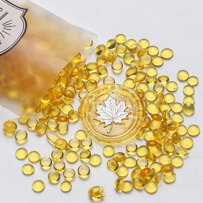 A pile of small, translucent yellow wax sealing beads scattered on a white surface.