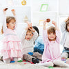 Trois jeunes enfants posent avec des petits cadeaux de fête western cowgirl sur un tapis blanc.
