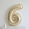 A large champagne gold foil number balloon shaped like the number six against a white background.