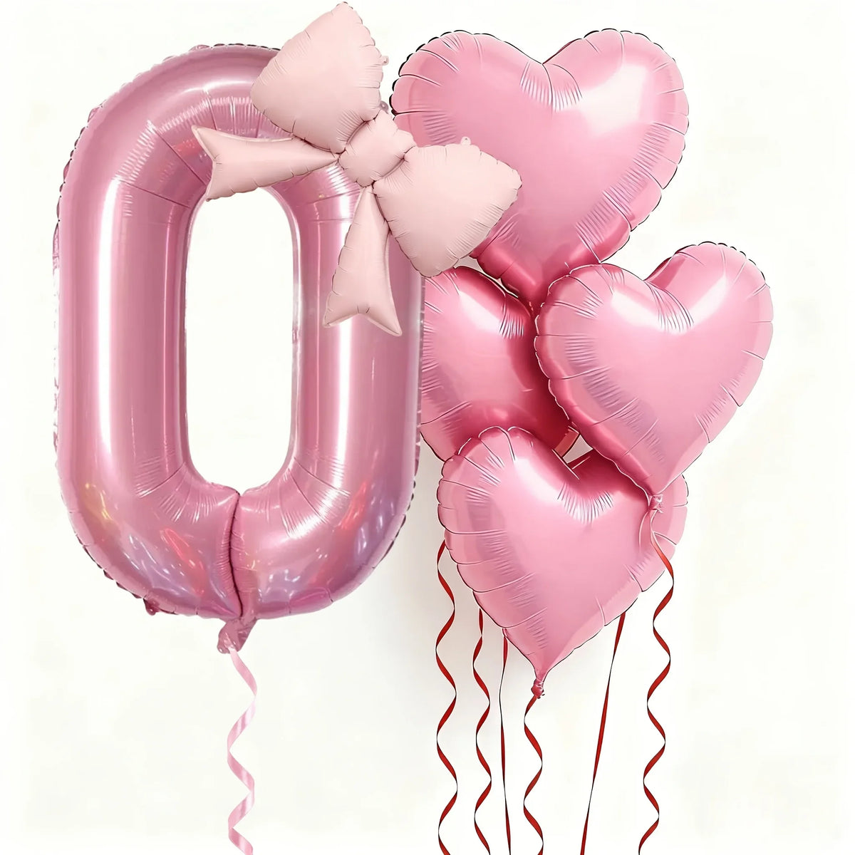 Pink foil balloons shaped like the number zero and hearts with pink bows for party decoration