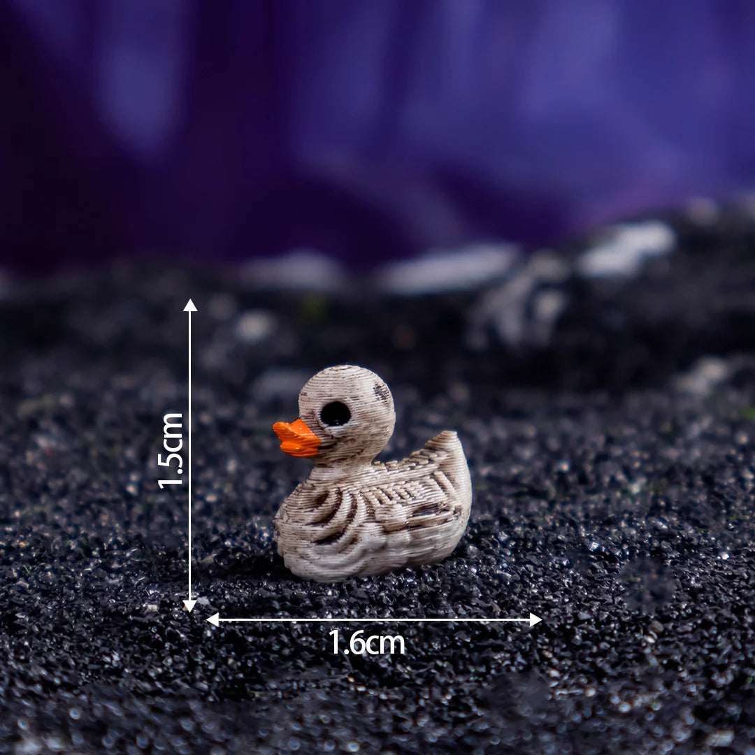 A small, light brown resin duck figurine with an orange beak resting on a dark surface.