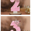 Pink glitter birthday candles shaped like the numbers 2 and 3 with crown designs