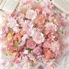 A dense arrangement of pink, peach, and cream silk artificial flower heads for crafting and decor.