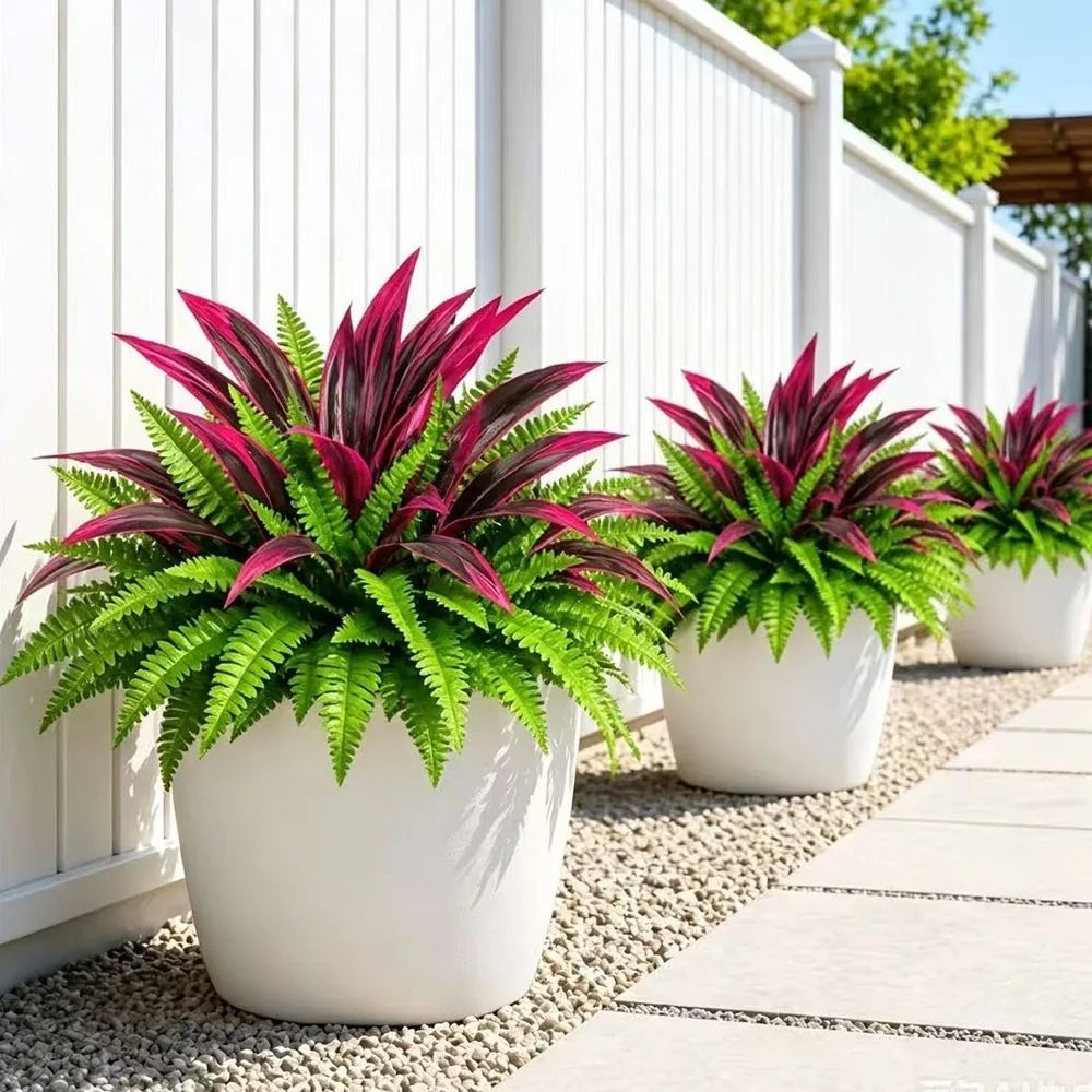 A potted artificial Dracaena Boston fern with vibrant pink and green leaves sitting on a white fence.