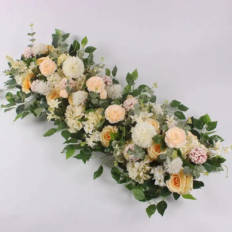 A lush floral arrangement featuring white, cream, and peach roses and greenery for event decor.