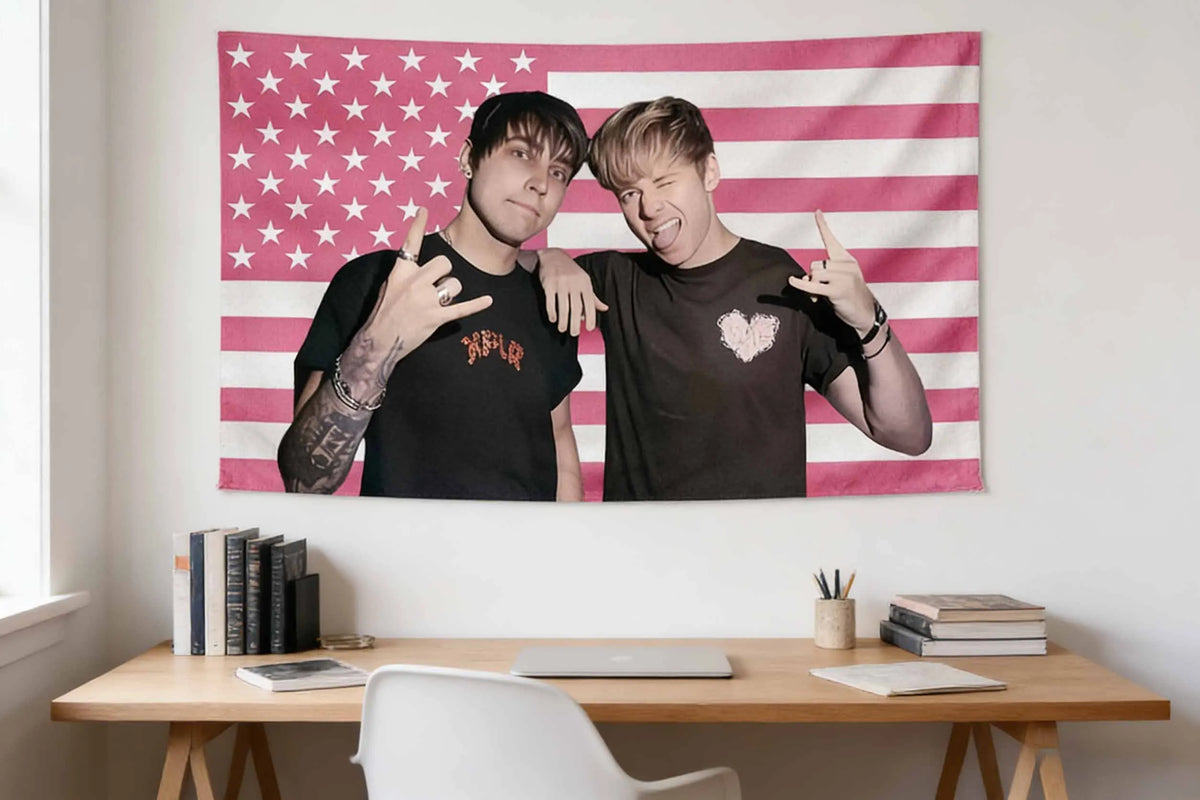 A portrait of two young men making peace signs against an American flag tapestry.