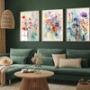 Three canvas prints featuring colorful retro wildflower landscapes displayed on a green sofa.